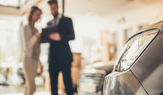 A man and a woman looking at a clipboard by two vehicles