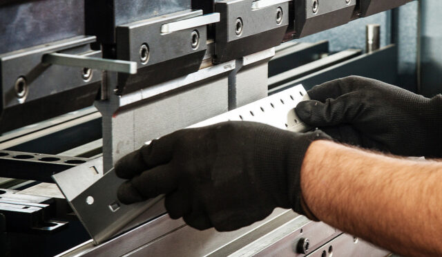 A man bending a piece of metal with a machine