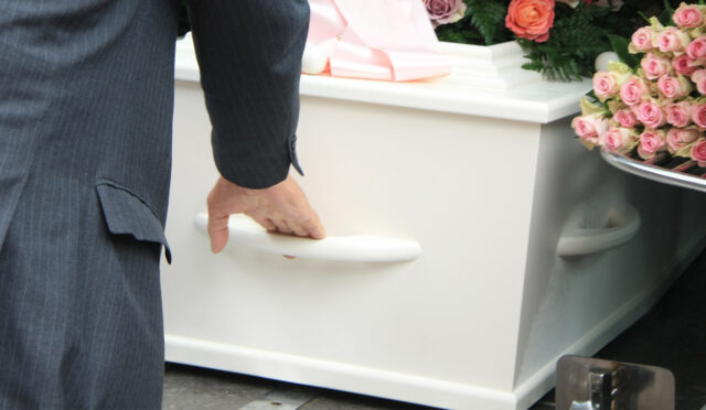 A man removing a casket from a vehicle